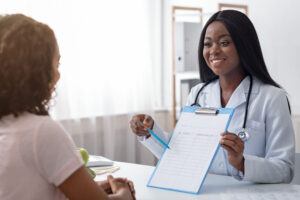 Black female doctor showing information on a clipboard to patient